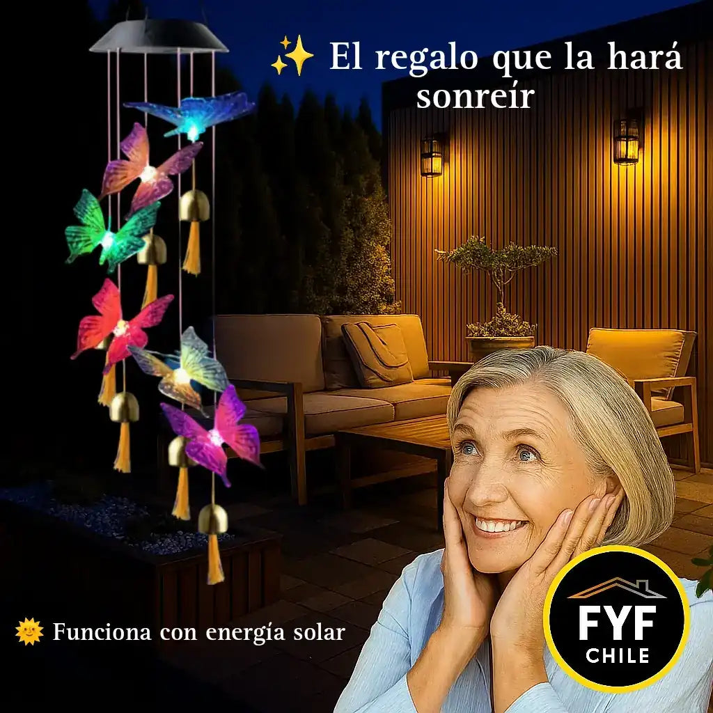 Colgante solar de mariposas iluminado en una terraza de noche, con una mujer adulta sonriendo al mirarlo, rodeada de luces cálidas y decoración elegante