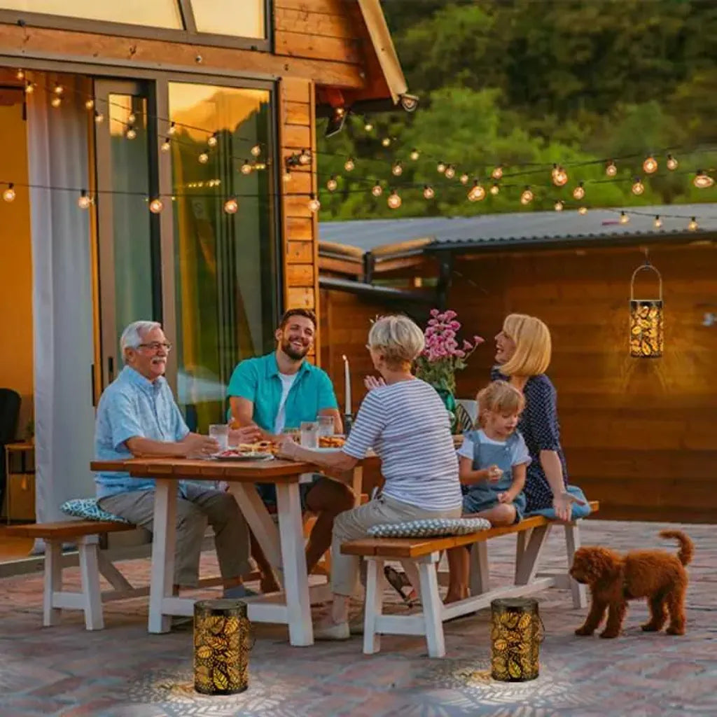 Familia compartiendo al aire libre con faroles solares decorativos iluminando el patio al atardecer