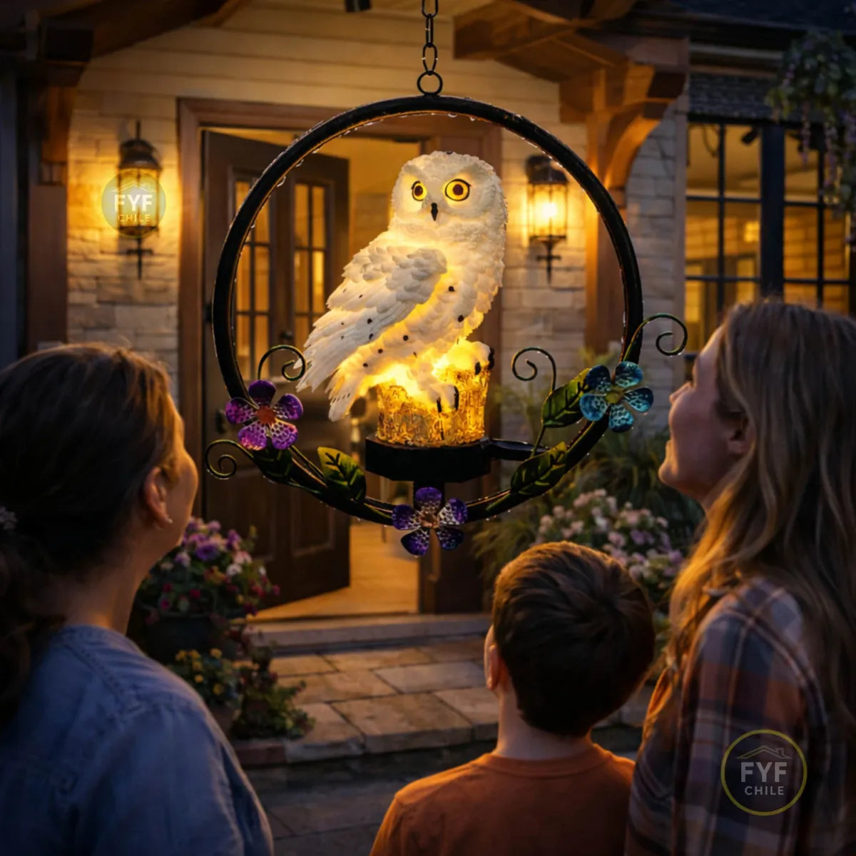 Colgante solar de búho LED iluminado en la entrada de una casa mientras una familia lo admira de noche
