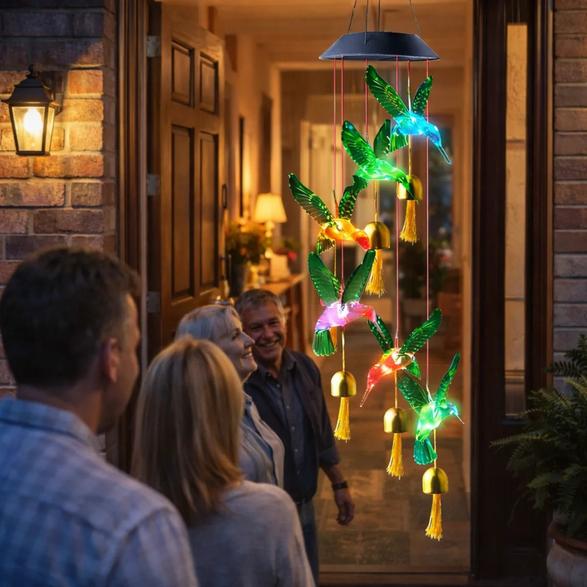 Colgante solar de colibríes LED multicolor en la entrada de una casa iluminando el ambiente y sorprendiendo a las visitas.