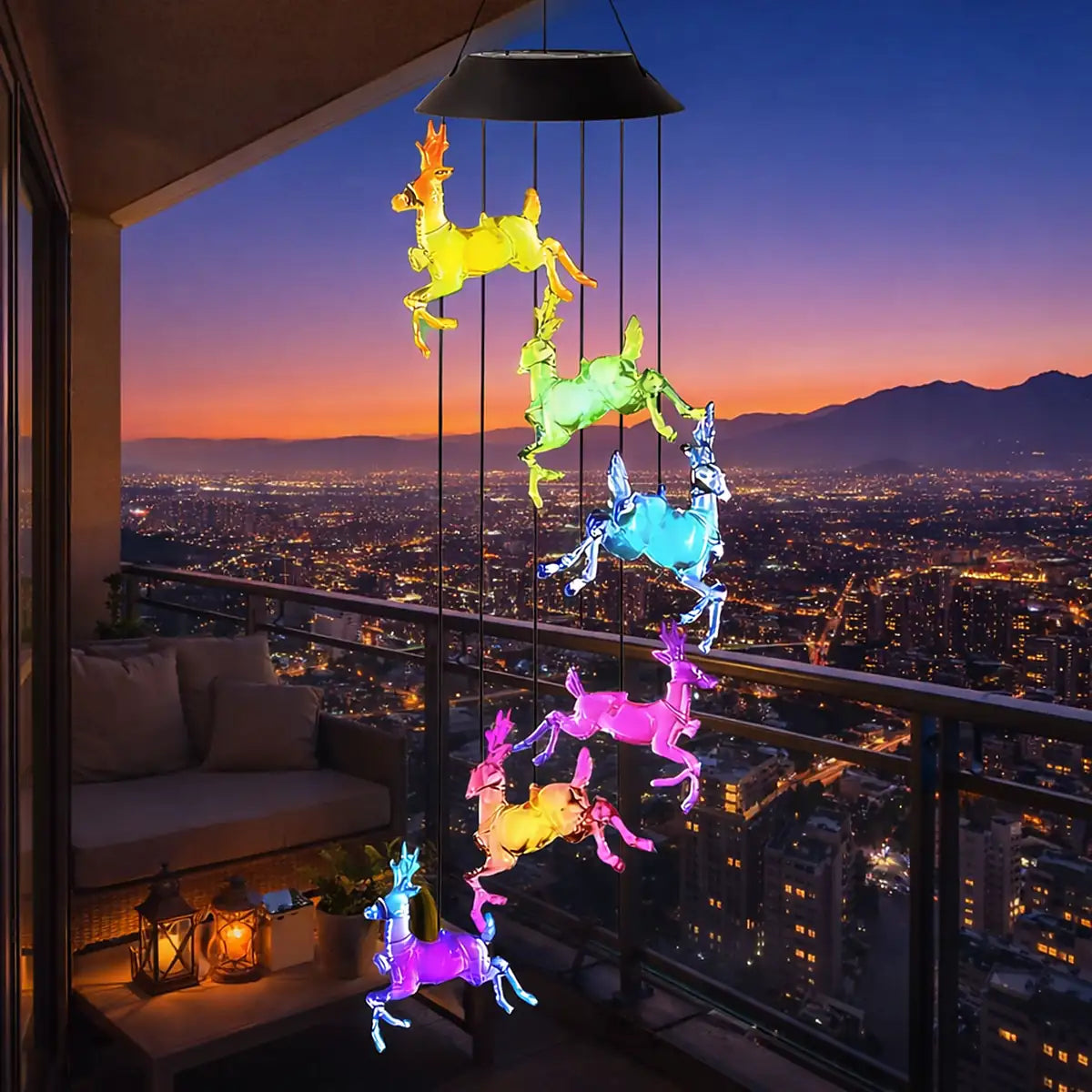 Colgante solar de renos LED multicolor en balcón de departamento con vista nocturna a la ciudad y cordillera