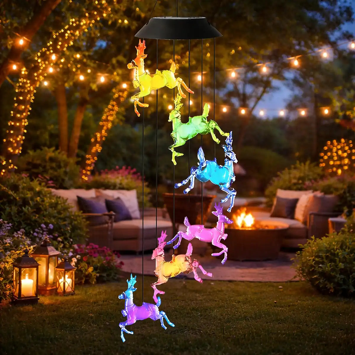 Colgante solar de renos LED multicolor en jardín acogedor con luces cálidas, faroles y fogón exterior nocturno