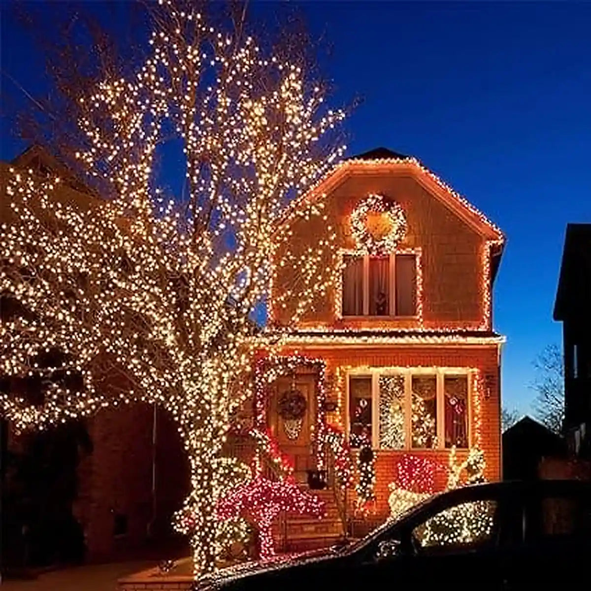 Luces solares decorativas iluminando árbol y casa en Navidad con ambiente cálido nocturno